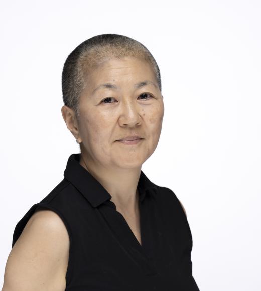 Headshot (photograph) of person with close-cropped hair, sleeveless black top, neutral expression
